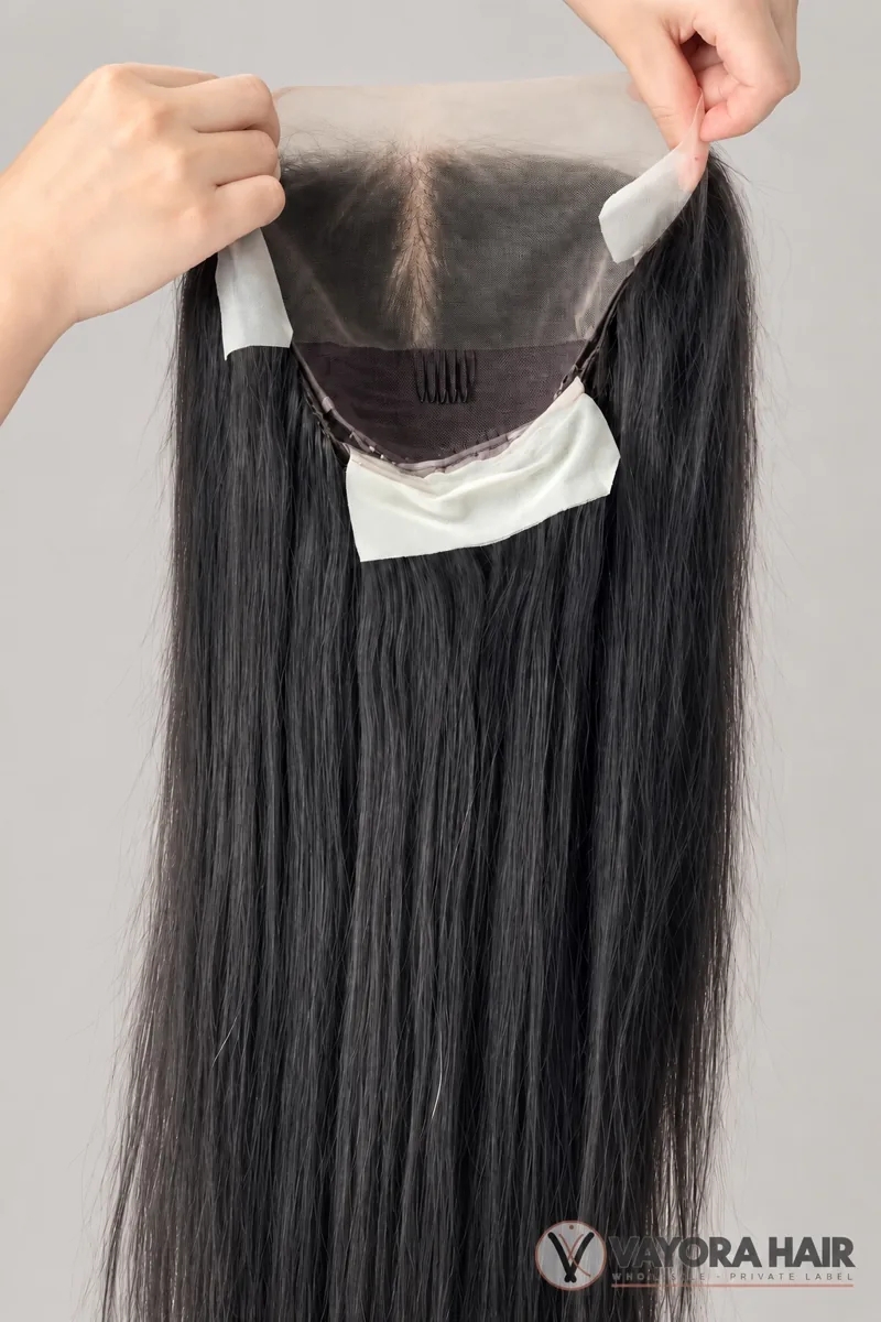 Hands showing the inner cap and front lace of a dark long wig