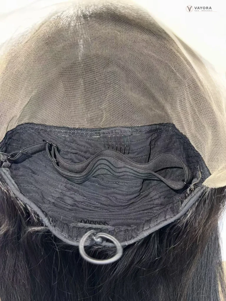 Inside view of a glueless wig showing lace mesh, weft stitching, a wide elastic band, combs and an adjustable drawstring.