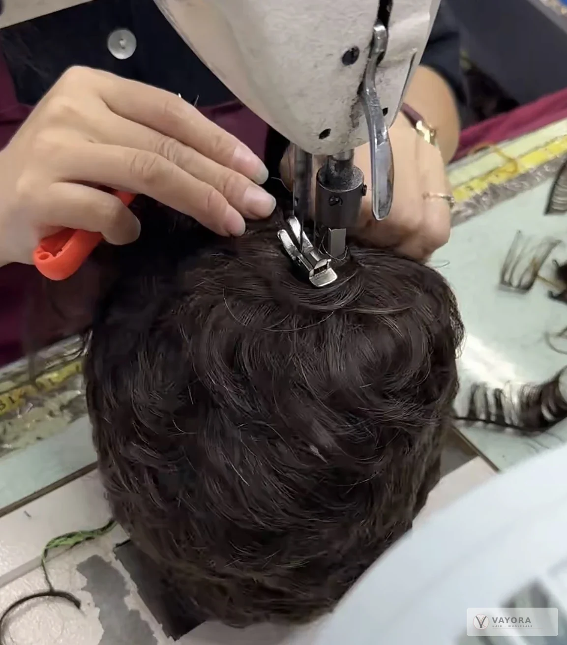 Machine sewing on a wig at VAYORA’s Xuchang manufacturing partner facility.