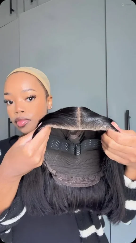 Person holding an open wig to show the cap interior, combs and stitching